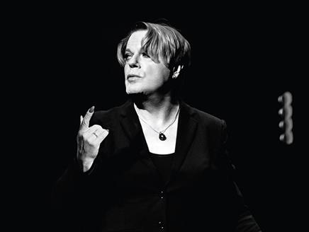 A black and white picture of Eddie Izzard on stage.
