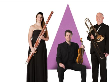 Three musicians are holding their instruments in front of a purple triangle graphic.