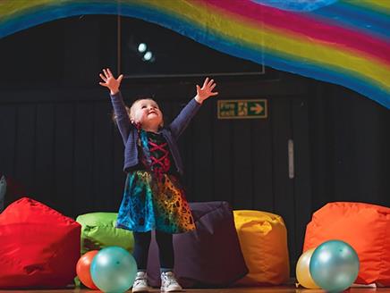 Press shot for Filskit Theatre: Wonder Gigs. featuring a small child listening to music in multicoloured surroundings.