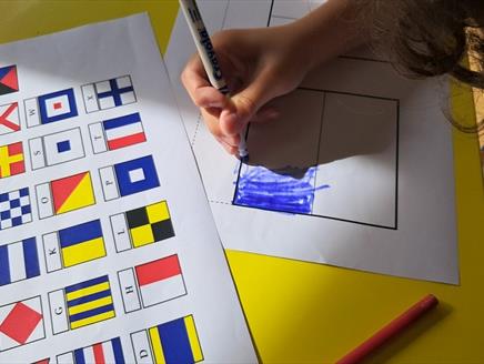 A child colouring in flag sheets to spell out a name
