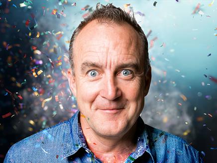 Head and shoulders shot of comedian Jimeoin with confetti around him.