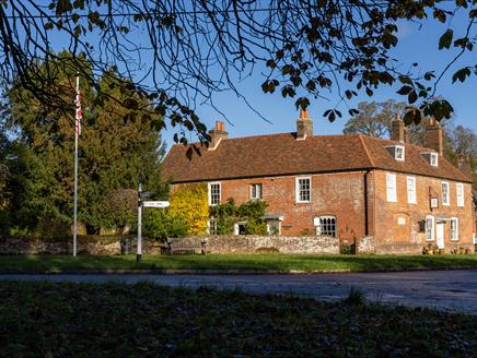 Jane Austen's House from the garden in Autumn.  Brown and orange leaves carpet the ground.