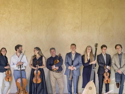 A group of musicians holding various string instruments stand in a line.