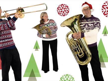 Three performers from the Bournemouth Symphony Orchestra with their instruments and Christmas jumpers