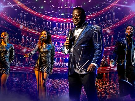 A vibrant concert scene with a Luther Vandross tribute dressed in a sparkling suit, holding a microphone. He is accompanied by three backup singers, a