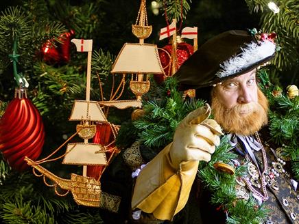 King Henry dressed for Christmas, with a tree design in the background.