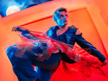 Nikita Kuzmin is dressed in a stylish outfit, blending modern and theatrical elements, with flowing, translucent fabric, adding a sense of movement. T