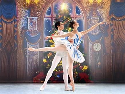 A male and female ballet dancer. The female dancer is doing an arabesque in a blue and white striped tutu. The male dancer is in an a white leotard an