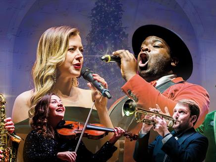 Vocalists and instrumentalists in front of a Christmas tree