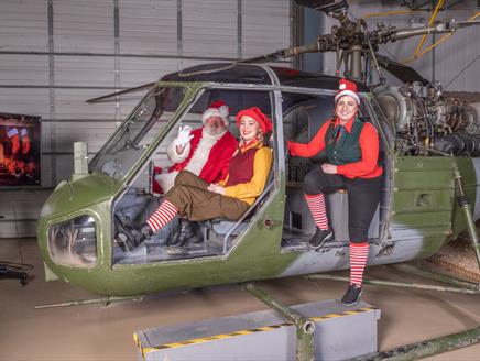 Santa and two elves in a helicopter at the Army Flying Museum
