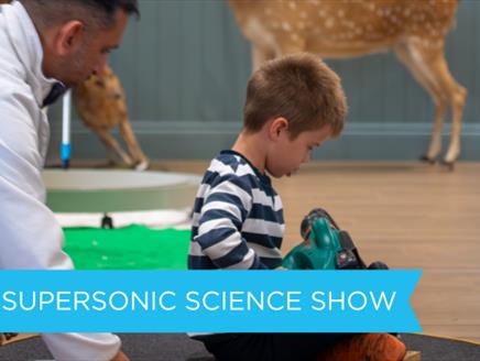 Child sitting on a hoover vacuum at a science demonstration.