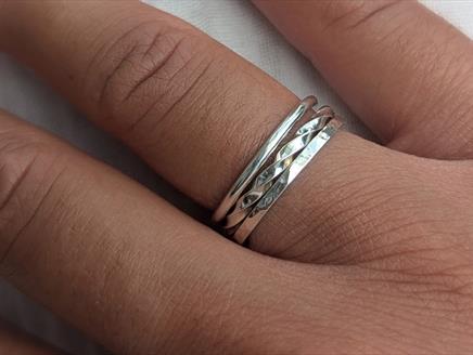 A close up of a person's hand, wearing stacking rings