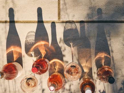 Bottles of wine lined up and their shadows reflected in the sunshine
