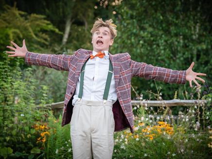 Actor in garden setting with arms out in joyful manner