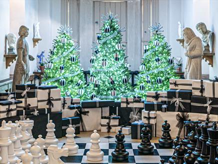 Sparkling Christmas trees illuminate a giant chess board in The Vyne's Stone Gallery.