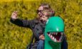 A woman and child sit on George's Dinosaur ride at Peppa Pig World