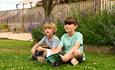 Two children sit on the grass at Green Hill Farm