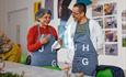 Image of two people attending a creative workshop at John Hansard Gallery. They are wearing JHG aprons and having a conversation.