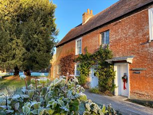  Jane Austen's House in winter.  Frost is on the ground and a red wreath decorates the door. 