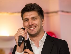 A man smiling whilst holding a microphone