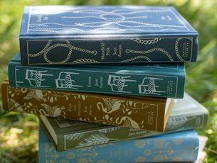 Beautiful clothbound editions of Jane Austen's novels stacked on the grass in Jane Austen's garden