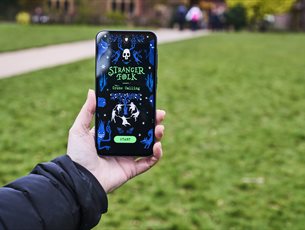 A hand holds a mobile phone with the event app open.