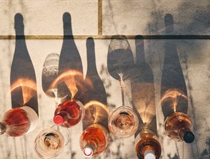 Bottles of wine lined up and their shadows reflected in the sunshine