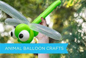 child arm point up with  a dragonfly balloon model in its hands within a background of greenary.