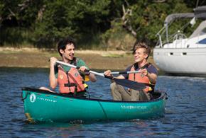 Two people splashing about on the water in a canoe.