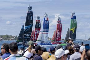 Image of F50 catamarans racing on water with crowd watching in the foreground