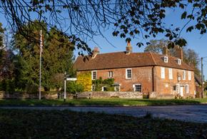 Jane Austen's House from the garden in Autumn.  Brown and orange leaves carpet the ground.