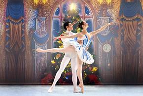 A male and female ballet dancer. The female dancer is doing an arabesque in a blue and white striped tutu. The male dancer is in an a white leotard an