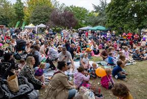 Lots of family groups sat on grass with gazebos in the background.