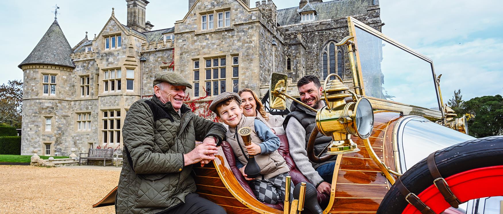 Family in Chitty Chitty Bang Bang outside Palace House, Beaulieu