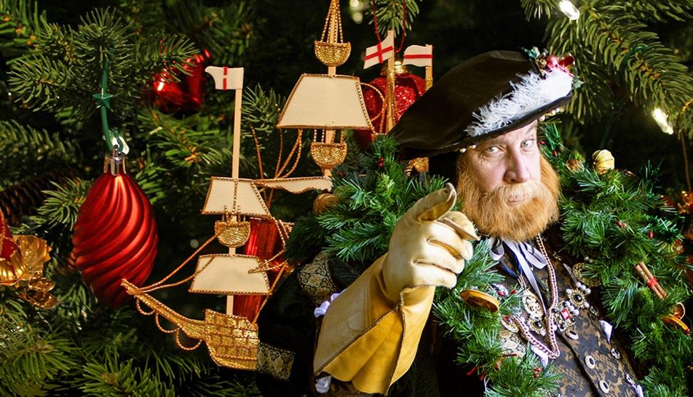 King Henry dressed for Christmas, with a tree design in the background.