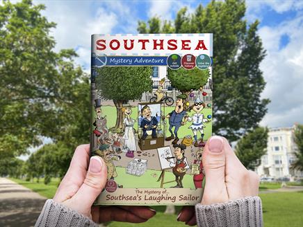 Southsea Treasure Hunt Adventure: The Mystery of The Laughing Sailor guide book in hand