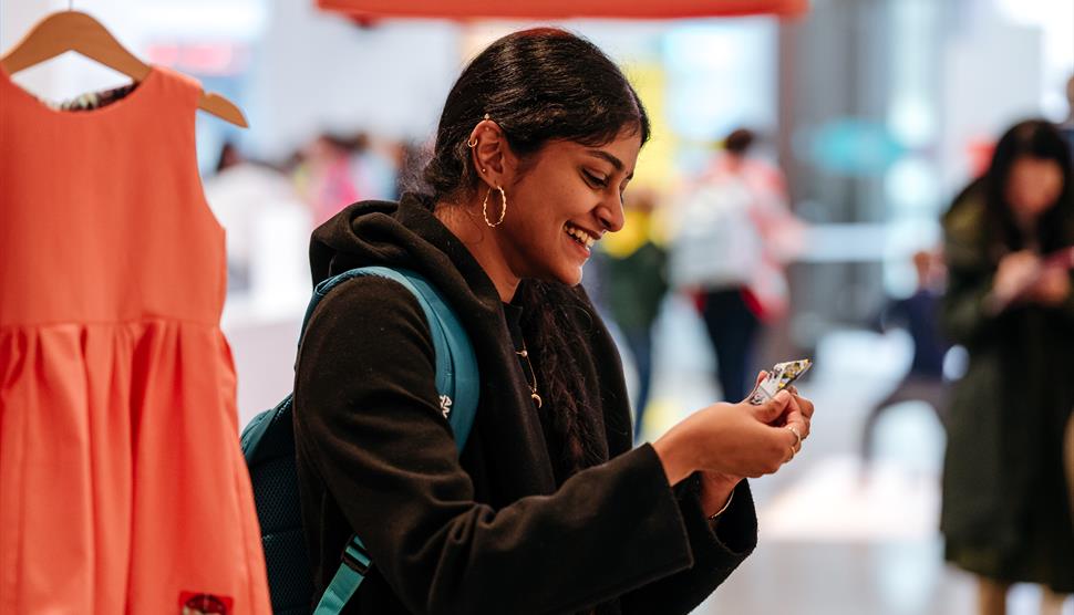 a young person with long dark hair watching a paper boat origami in their hand while attending an exhibition. a young person with long dark hair watching a paper boat origami in their hand while attending an exhibition.