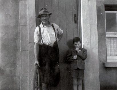 old black and white photograph of man and boy standing in doorway