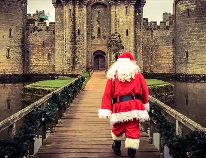 Father Christmas walking over the bridge to Bodiam Castle