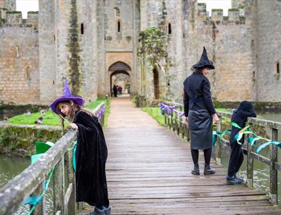 Children in witch costumes explore the bridge to Bodiam Castle during the Spell Quest family trail.