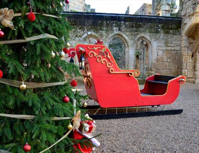 Christmas at Bodiam Castle with a decorated tree and festive sleigh set among historic medieval stone ruins.