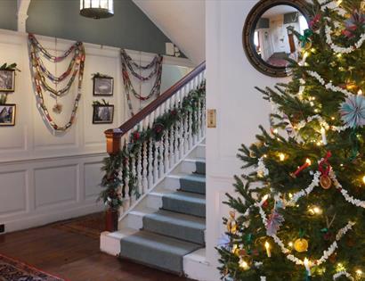 Christmas at Lamb House featuring a decorated tree, festive garlands and a historic staircase adorned for the season.