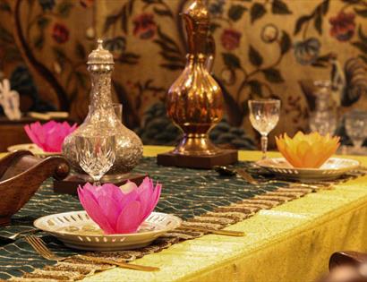 Festive Diwali dining table at Bateman’s with lotus decorations, glassware and gold-toned table settings.