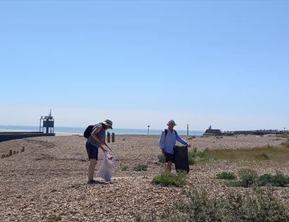 Two people with bin bags on a beach litter picking.
