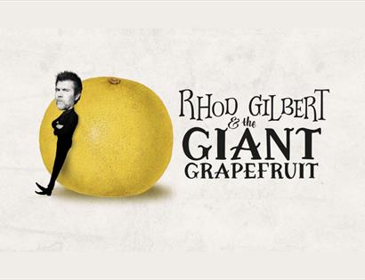 Rhod Gilbert leaning on a large grapefruit