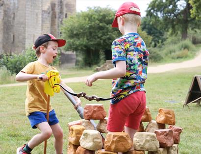 two young children with hobby horse and archery bow at Bodiam Castle.