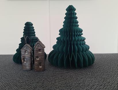 Photograph of paper 3d christmas tree in concertina style. In font is a small model of elongated huts.