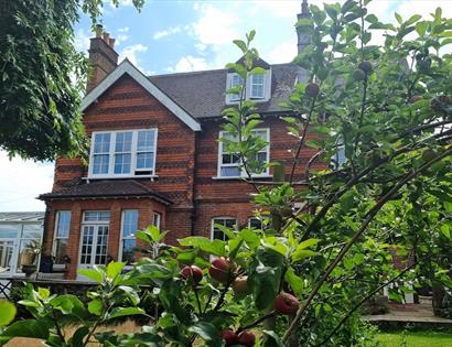 Photograph of a detached house with a conservatory and garden.