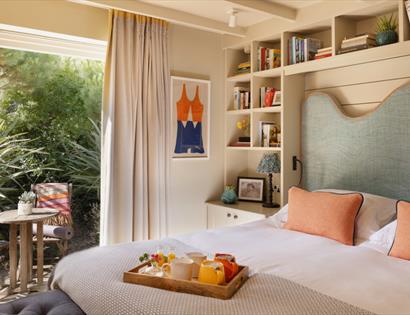 Elegant guest room at The Gallivant with garden terrace, reading nook and breakfast tray.
