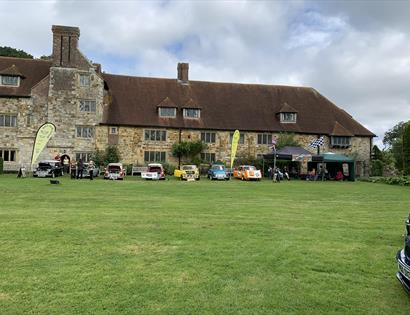 cars on a lawn in front of historic brick property.